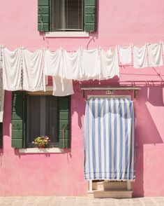 a pink building with green shutters and an awning