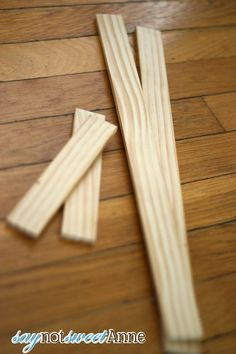 two pieces of wood sitting on top of a wooden floor next to a pair of scissors