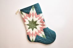 someone is holding up a quilted stocking on the wall, which has a star design