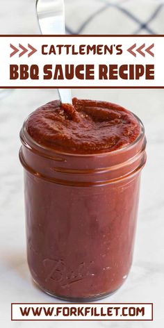 a jar filled with bbq sauce sitting on top of a counter next to a spoon