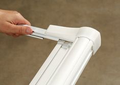 a hand is holding onto the handle of a white window sealer that's attached to an outside door