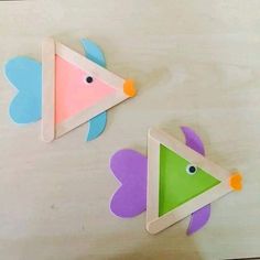 two colorful fish shaped magnets sitting on top of a wooden table