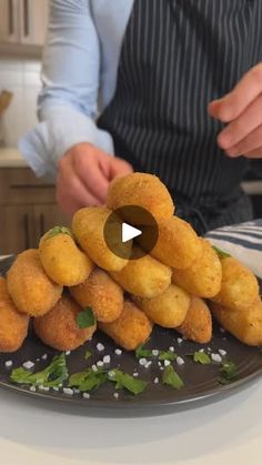 a plate full of fried food sitting on top of a table next to a person