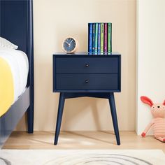 a blue nightstand with books on it next to a bed and a toy bunny rabbit