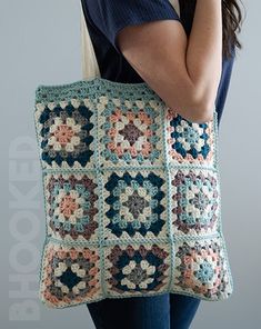 a woman is holding a crocheted bag