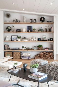 a living room filled with lots of furniture and bookshelves on top of wooden shelves