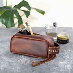 Handcrafted Leather Dopp Kit for Men, Leather Toiletry Bag 𝗜𝗱𝗲𝗮𝗹 𝗚𝗶𝗳𝘁: Ideal for birthdays, anniversaries, groomsmen gifts, Valentine's Day, Father's Day, and more. A thoughtful gift for your boyfriend, husband, or any significant man in your life. 𝗜𝗱𝗲𝗮𝗹 𝗦𝗶𝘇𝗲 𝗳𝗼𝗿 𝗧𝗿𝗮𝘃𝗲𝗹: Its compact design fits easily into larger travel bags, making it an excellent choice for all types of travel. 𝗠𝗮𝘁𝗲𝗿𝗶𝗮𝗹: Experience the luxury and durability of high-quality full-grain leather. 𝗛𝗮𝗻𝗱𝗺𝗮𝗱𝗲 𝗚𝗶𝗳𝘁: Each piece is meticulously handmade, ensuring a unique and personal touch. 𝗖𝗮𝗽𝗮𝗰𝗶𝘁𝘆: Equipped with 1 interior zip pocket, offering ample space for all grooming essentials like deodorant, shaving cream, razors, and more. Serves as a multi-purpose bag, ideal for cos Brown Leather Pouch With Smooth Grain, Brown Rectangular Pouch With Smooth Grain, Brown Leather Pouch As Gift, Leather Rectangular Pouch With Smooth Grain, Rectangular Leather Case, Engraved Groomsmen Gifts, Personalized Toiletry Bag, Monogram Wedding Gift, Mens Monogram