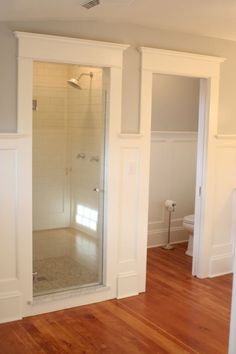 an empty bathroom with white walls and wood floors