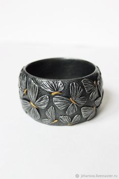 a black ring with leaves on it sitting on a white surface, in front of a white background