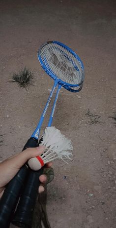 a person holding a tennis racket and ball in their hand, on the ground