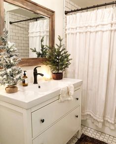 a white bathroom with a christmas tree on the sink counter and shower curtain behind it