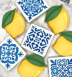 four decorated cookies with lemons and leaves on top of each cookie, sitting on a marble surface