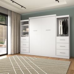 a white closet with clothes hanging on it's doors and drawers in front of a sliding glass door