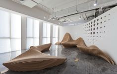 a large room with several wooden sculptures on the wall and floor, along with white walls