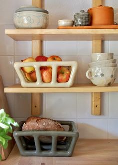 two shelves with bowls and fruit on them, one has an apple in the bowl