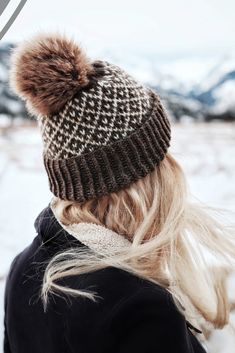 a woman with blonde hair wearing a brown and white pom - pom hat