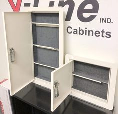 two white cabinets sitting next to each other on top of a black table with drawers