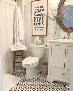 a white toilet sitting next to a sink in a bathroom under a framed sign on the wall