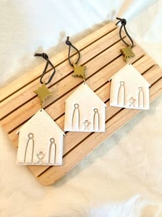 three small white houses are hanging on a wooden board with black string and star decorations