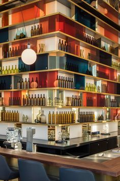 a bar with lots of bottles on the wall and chairs in front of it,