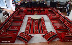 a large couch made out of red and black striped material with pillows on the floor