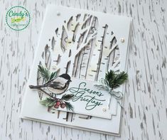 a white card with a bird on it and some pine branches in front of it