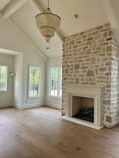 an empty living room with wood floors and stone fireplace