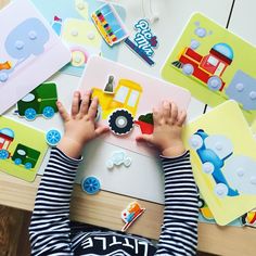 a child is playing with magnets on the table in front of their toy vehicles