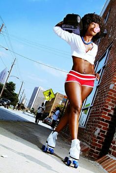 a woman in red shorts and white shirt leaning against a brick wall with her hand on her hip