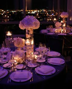 the table is set with white flowers and candles for an elegant dinner or reception at night