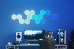 a desk with a computer and speakers on top of it in front of a blue wall