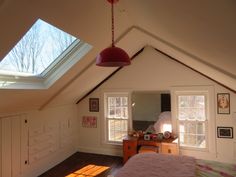 an attic bedroom with two windows and a desk in the corner on the far wall