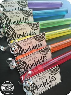 four different colored pens with labels on them and ribbons tied around the ends, sitting next to each other