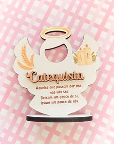 a wooden sign that says catequisita with an angel above it on a pink and white checkered background