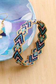 a pair of beaded bracelets sitting on top of a blue plate next to a bowl