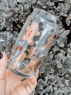 a person holding up a glass with a gingerbread design on it and snowflakes in the background