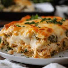 a white plate topped with lasagna covered in cheese and greens on top of a wooden table