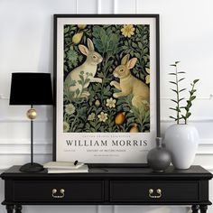 a black table topped with two white vases filled with flowers and plants next to a framed poster