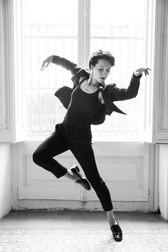 a woman in black and white is doing an acrobatic dance move on the floor