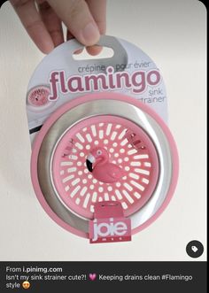 someone is holding up a pink and silver filamingo spinner in front of a white wall