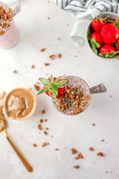 two glasses filled with granola, strawberries and yogurt on a table