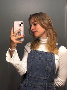 a woman taking a selfie in front of a mirror with her cell phone up to her ear