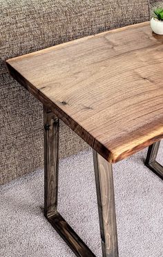 a wooden table sitting on top of a white carpeted floor next to a couch