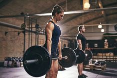 a man and woman in a gym doing squats with barbells on their backs