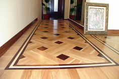 an empty hallway with wood flooring and framed pictures