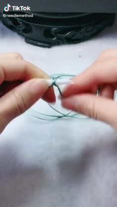 two hands are working on some string together