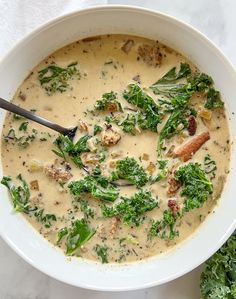 a white bowl filled with broccoli and meat soup on top of a table