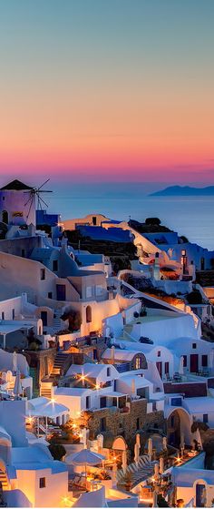 the sun is setting over some white buildings in oia, with an ocean view