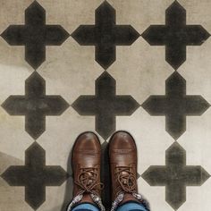 a pair of brown shoes sitting on top of a tiled floor