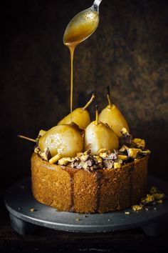 there is a cake with pears and nuts on the top, sitting on a plate